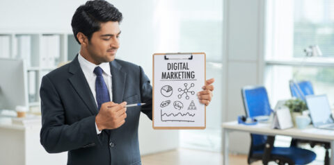 man-suit-standing-office-with-clipboard-pointing-poster-with-words